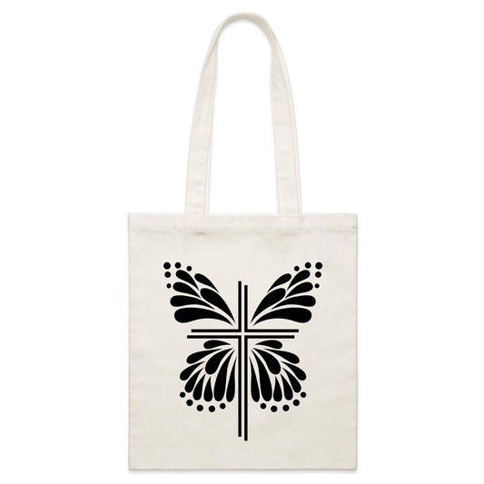 White tote bag with Black graphic. Graphic is of a cross with butterfly wings coming out of it.  Inspiration is from the bible; Therefore, if anyone is in Christ, he is a new creation. The old has passed away; behold, the new has come. 2 Corinthians 5:17