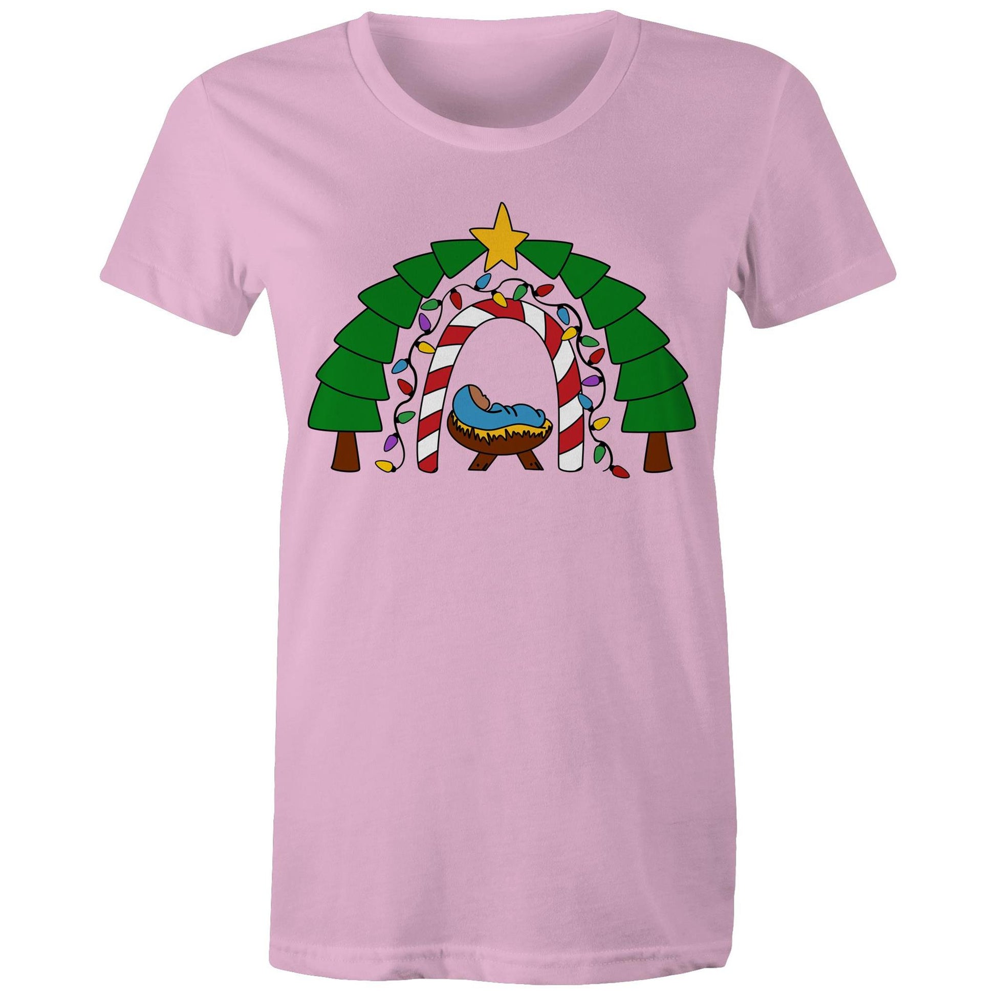 Women's Christian Pink T-shirt by Christianitee featuring a cosy nativity scene with baby Jesus in a manger, framed by a candy cane and Christmas light arch, evergreen trees, and a star. A festive design celebrating the joy and meaning of Christmas.